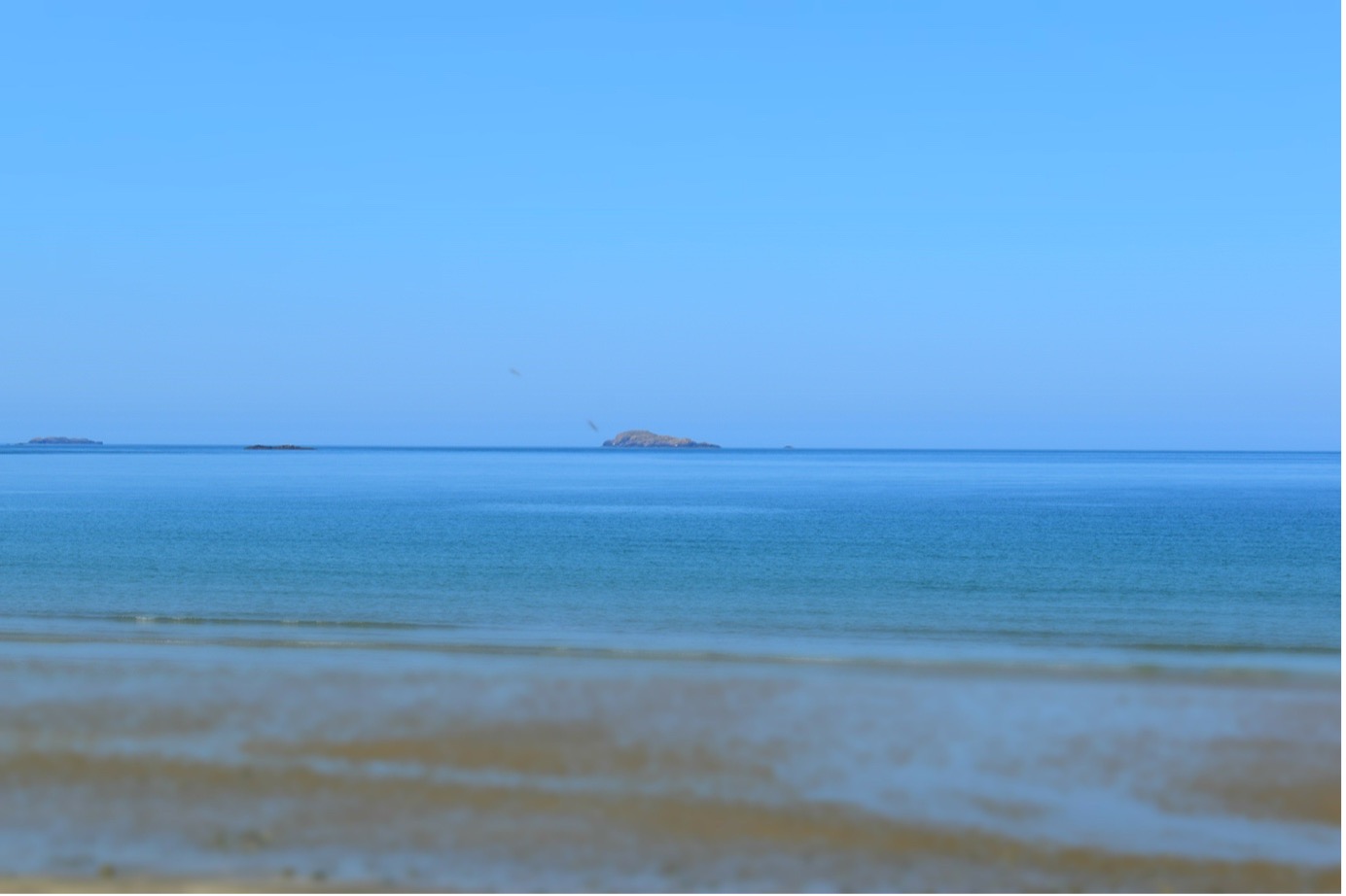 Blue sea and blue sky with a large rock from afar